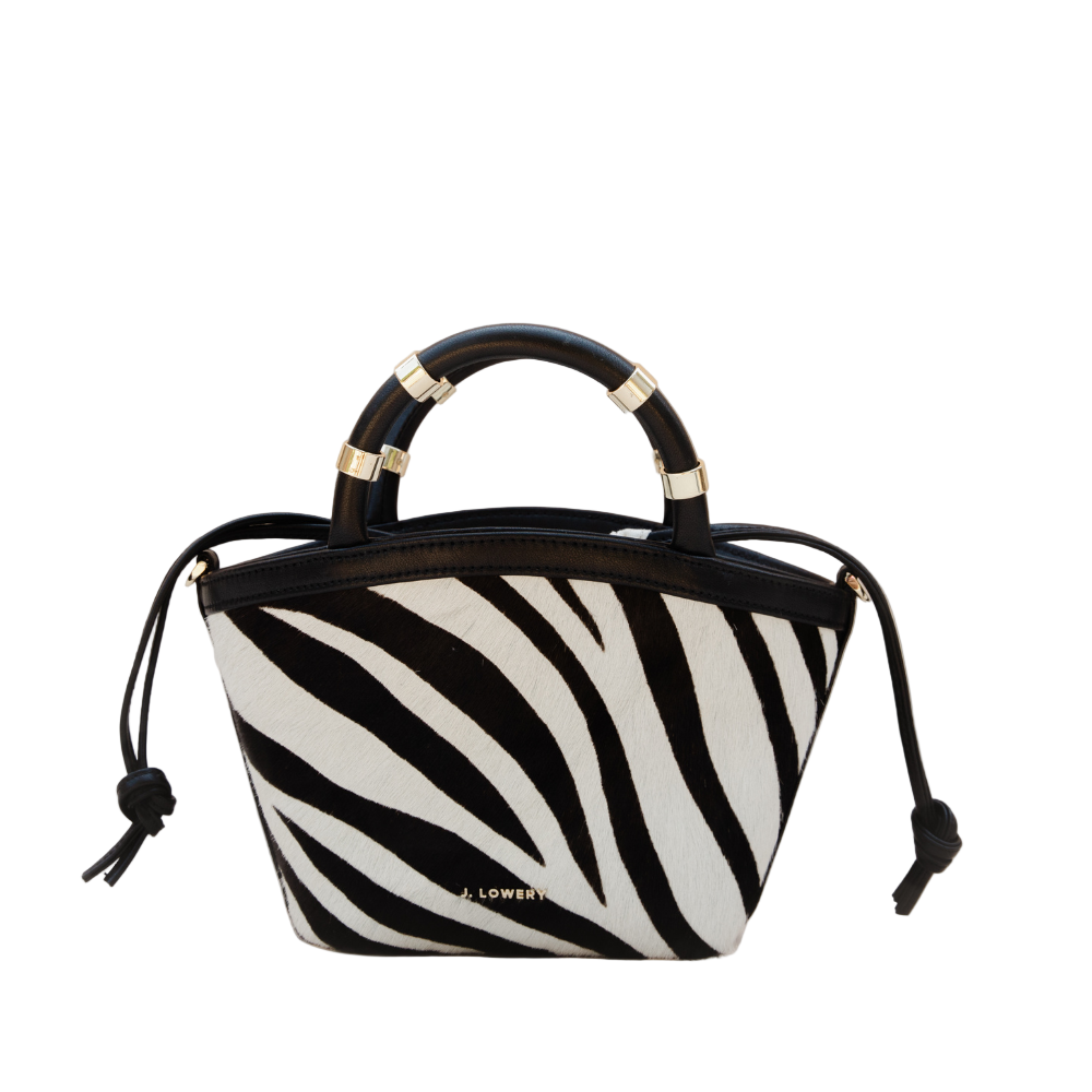 Zebra print handbag with black handle and drawstring on a beige background