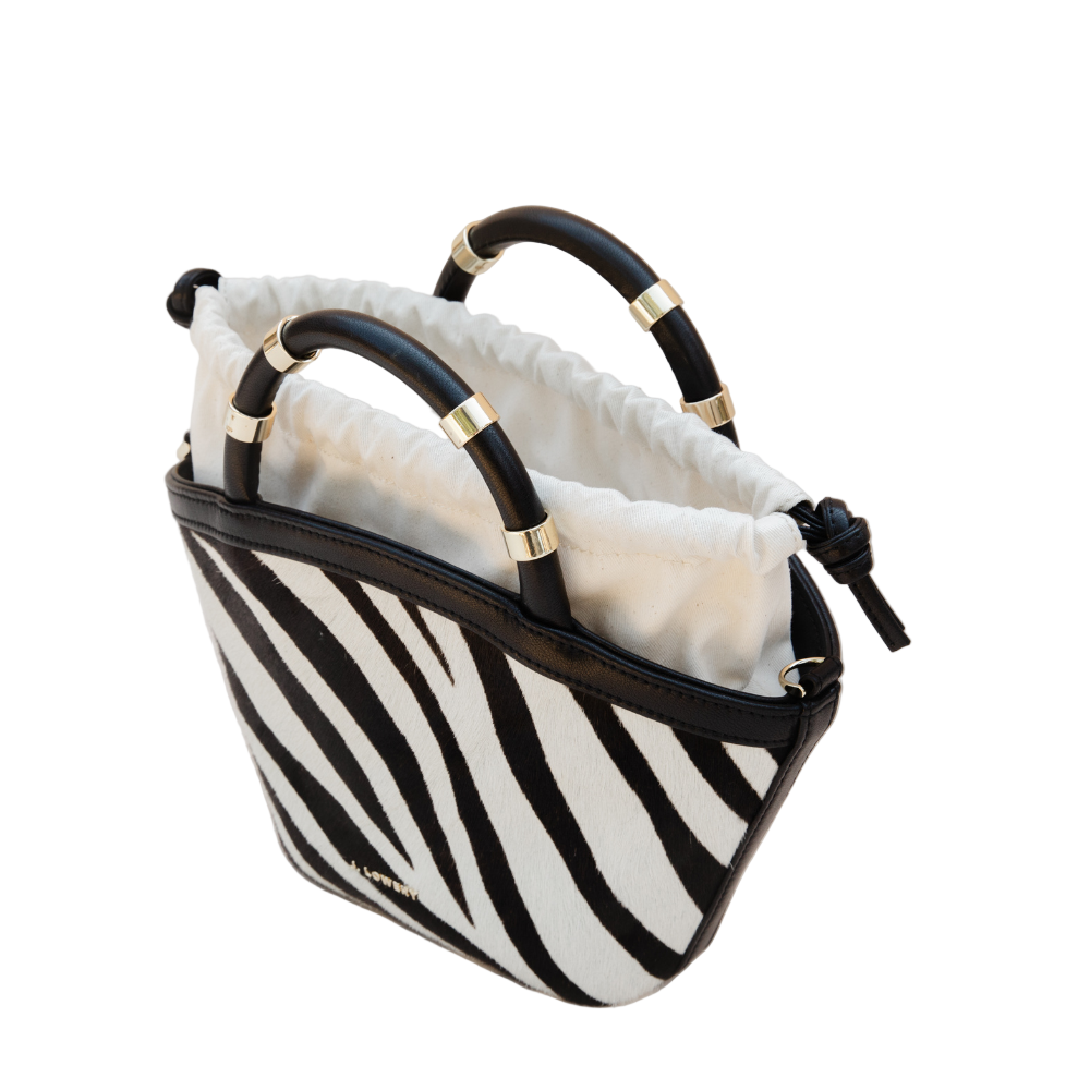 Black and white striped handbag with gold accents on a beige background