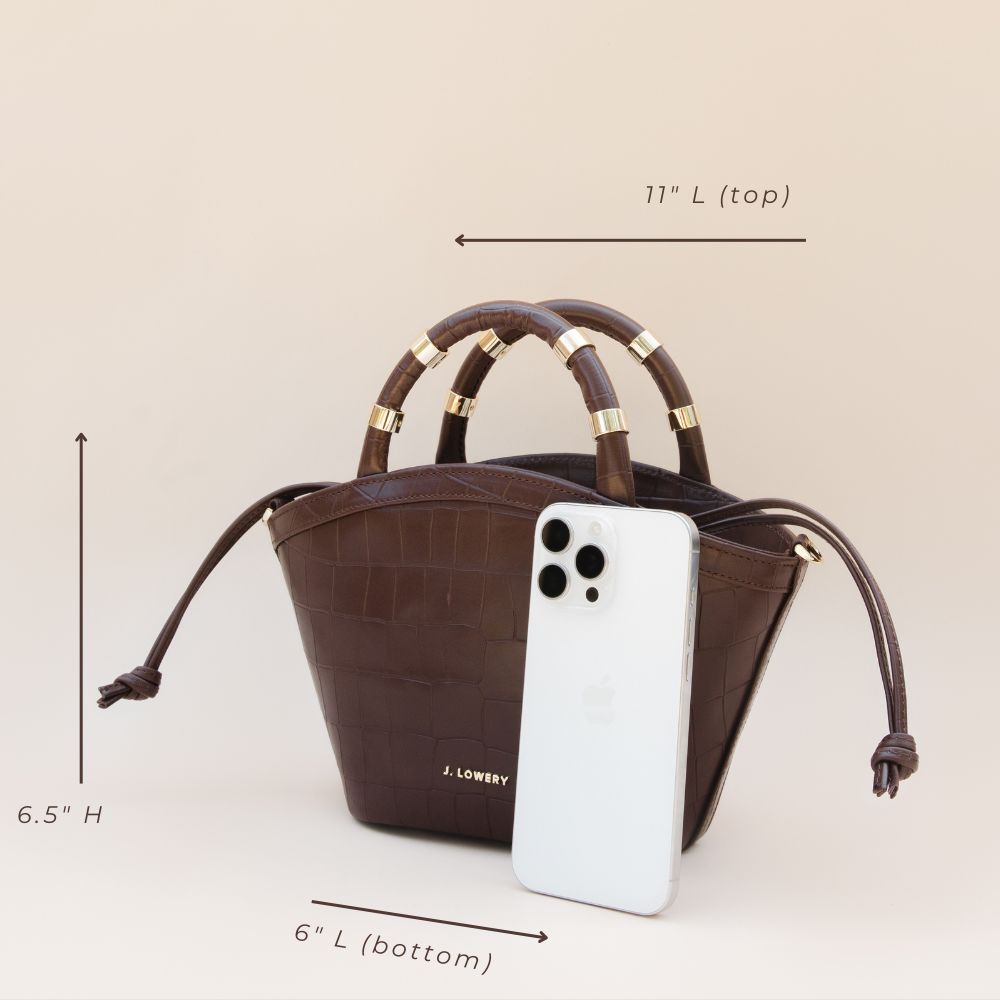 Brown handbag with gold handles and measurements, next to a white phone with 'J. Lowery' branding.