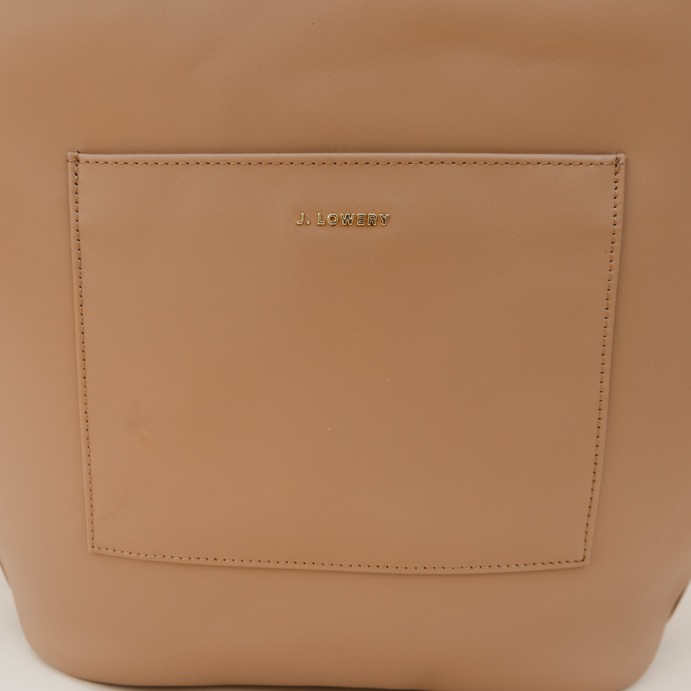 Close-up of a tan leather bag with 'J. Lothario' branding on a white background