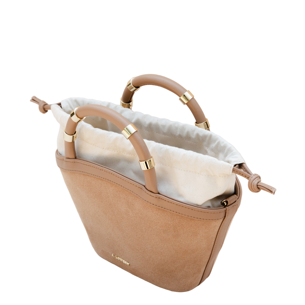 Beige handbag with gold accents on a beige background