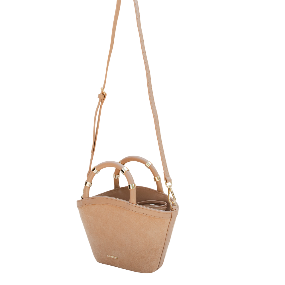 Beige handbag with gold accents on a beige background