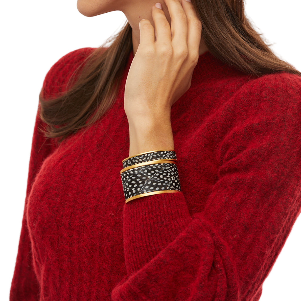 Person wearing a red sweater with a focus on a black and gold bracelet.