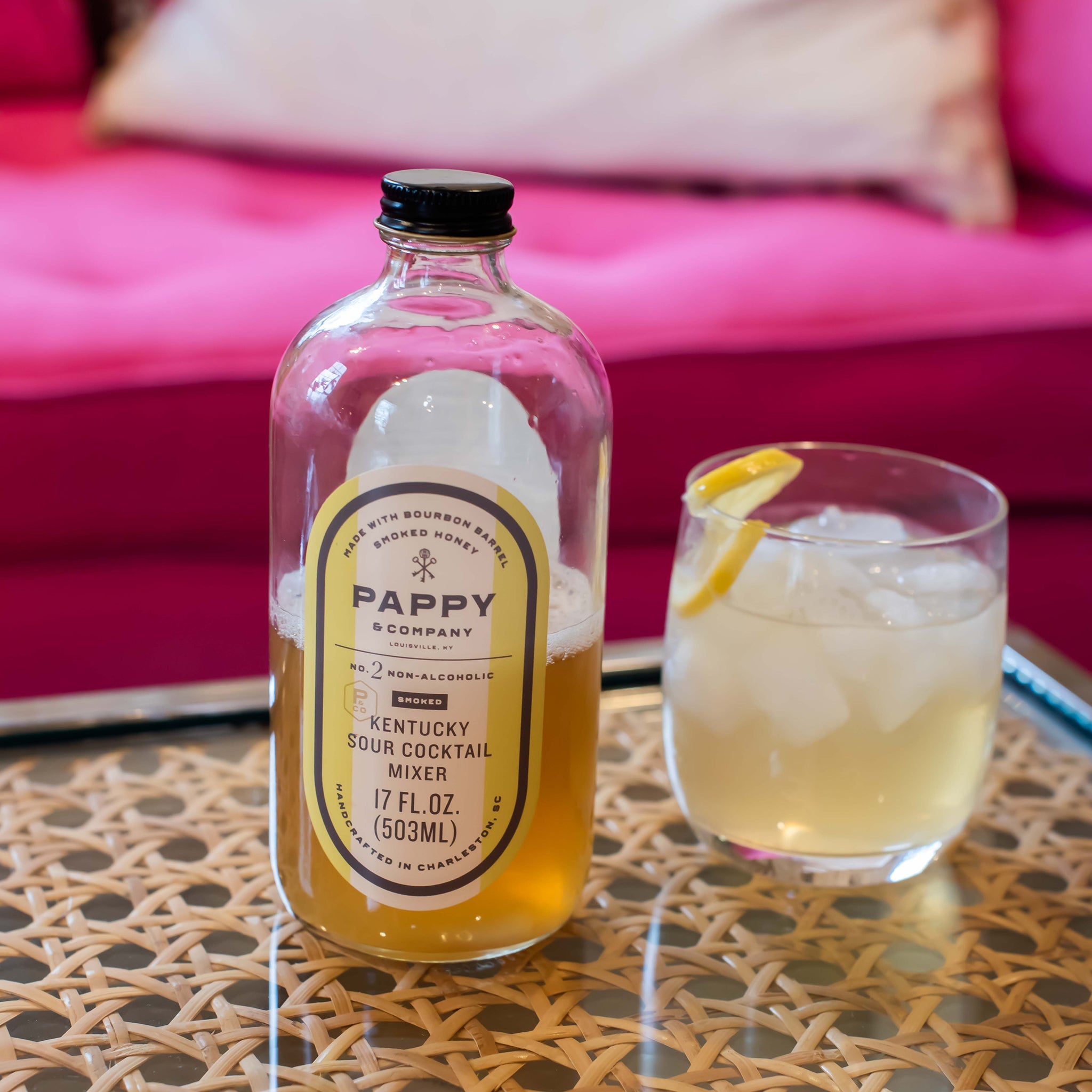 Pappy & Co. cocktail mixer bottle with a glass of lemonade on a table.