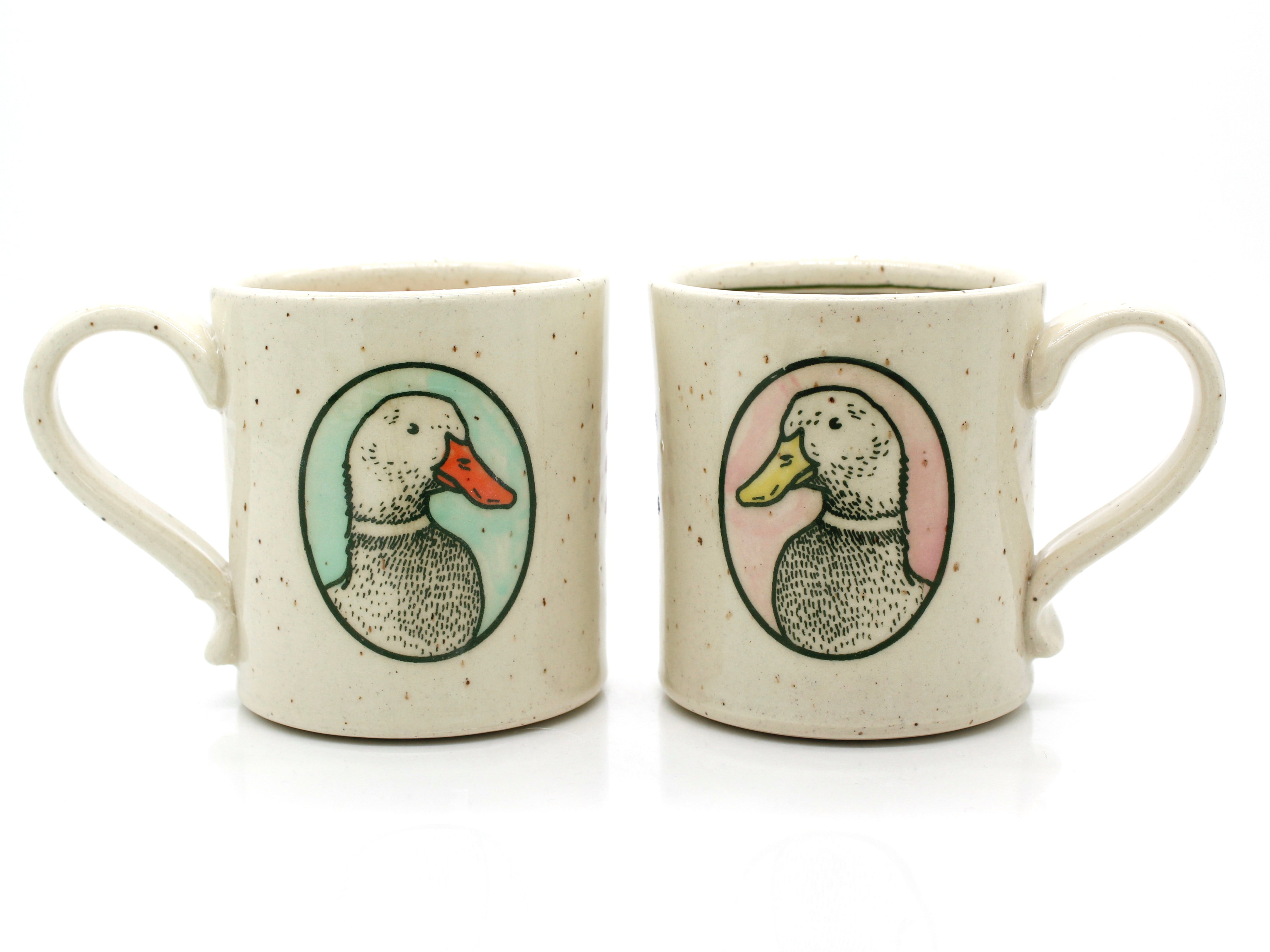 Two ceramic mugs with duck illustrations on a white background