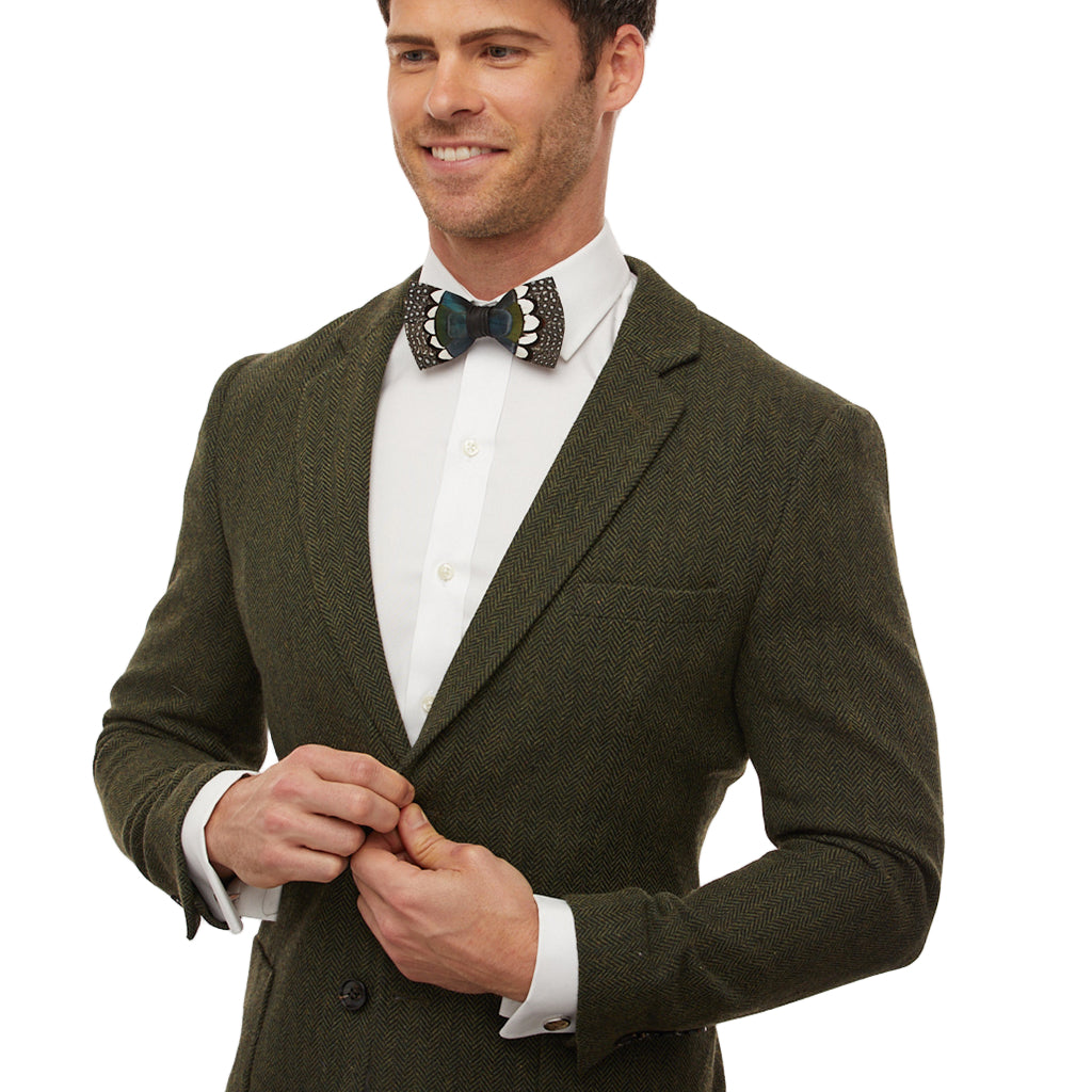 Man wearing a green suit jacket with a white shirt and patterned bow tie on a white background