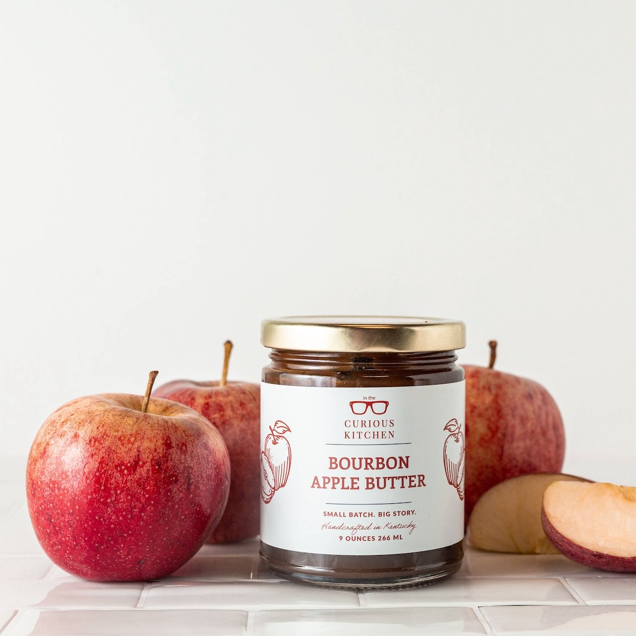 Jar of Bourbon Apple Butter with apples on a white background