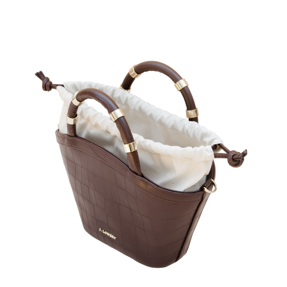 Brown handbag with gold accents on a beige background