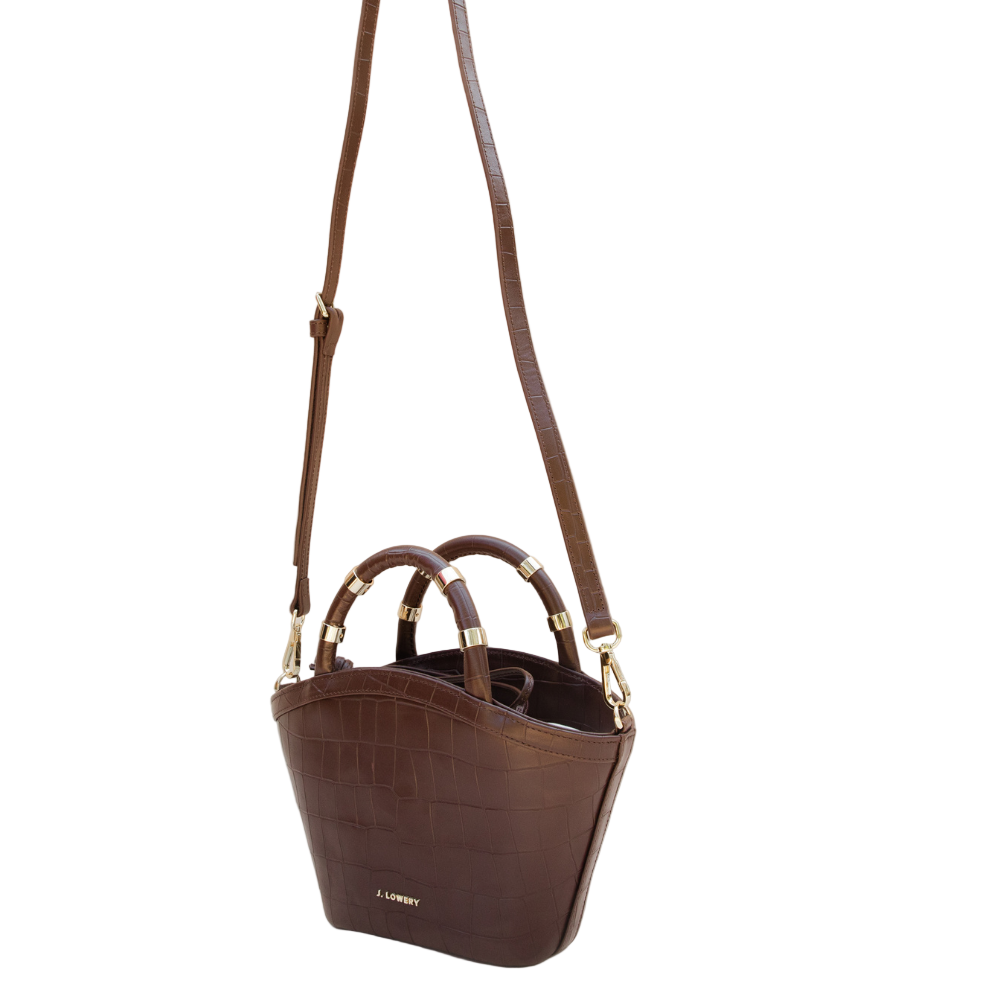 Brown handbag with gold accents on a beige background