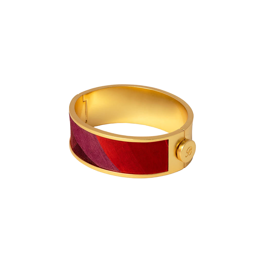 Gold bracelet with a red and purple band on a white background