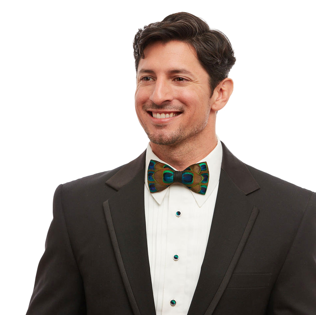 Man wearing a black tuxedo with a patterned bow tie on a white background