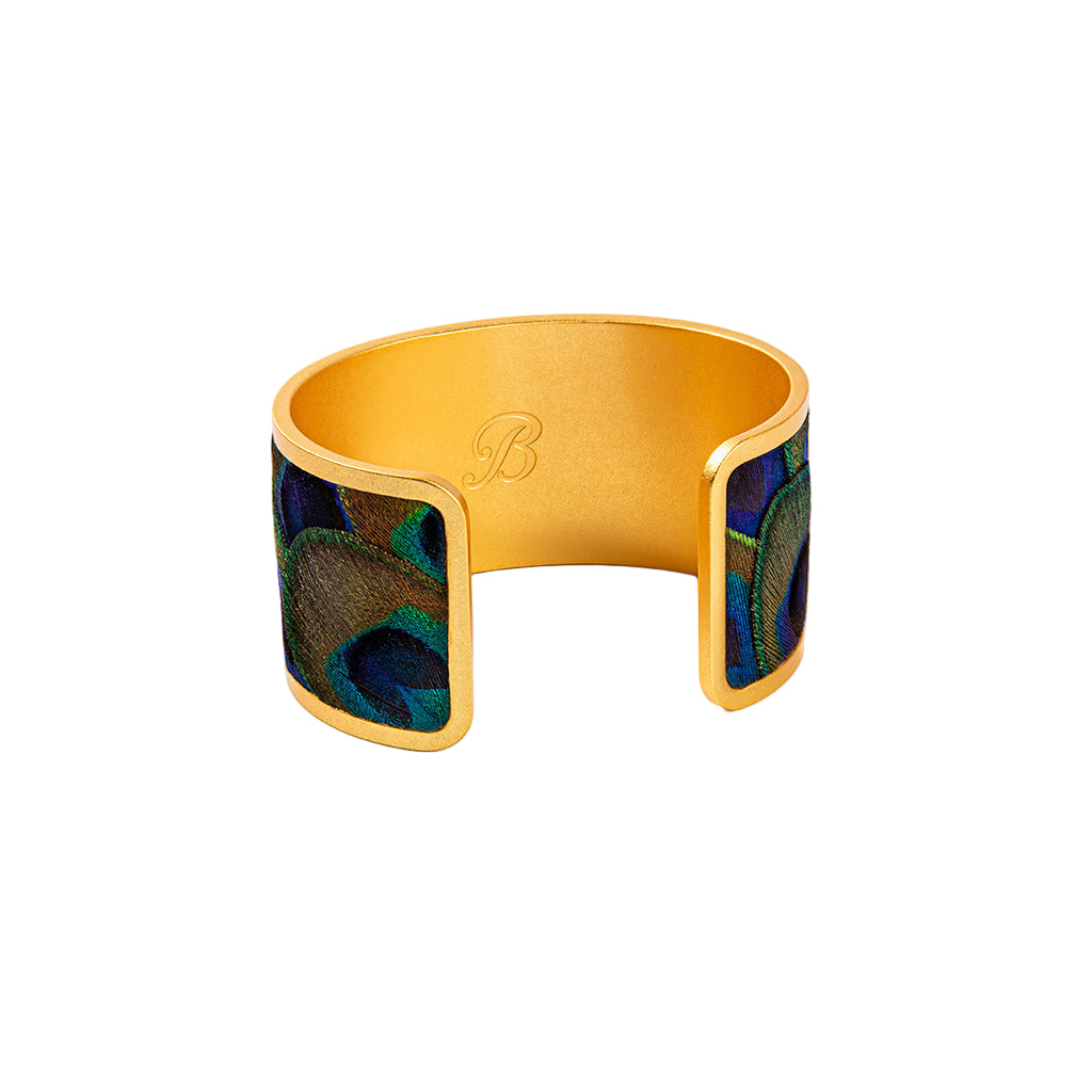 Gold bracelet with peacock feather design on a white background