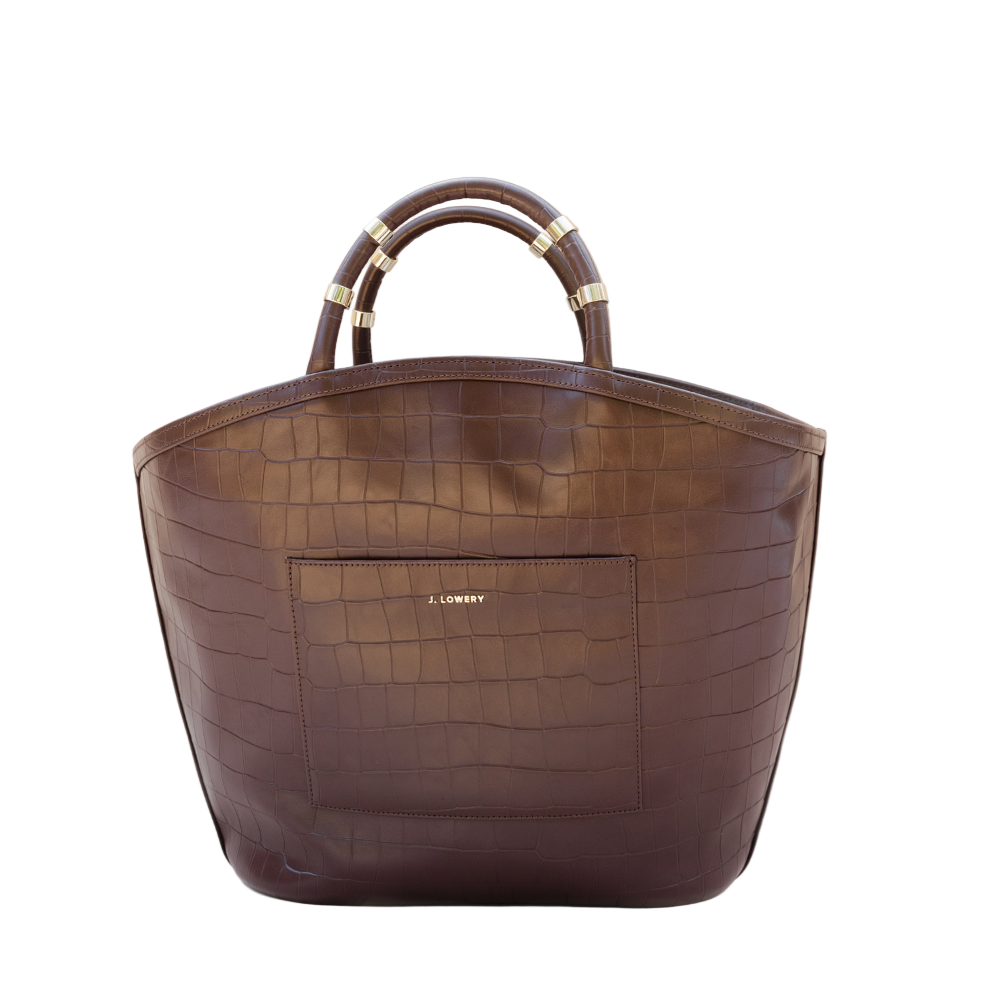 Brown leather handbag with gold accents on a beige background