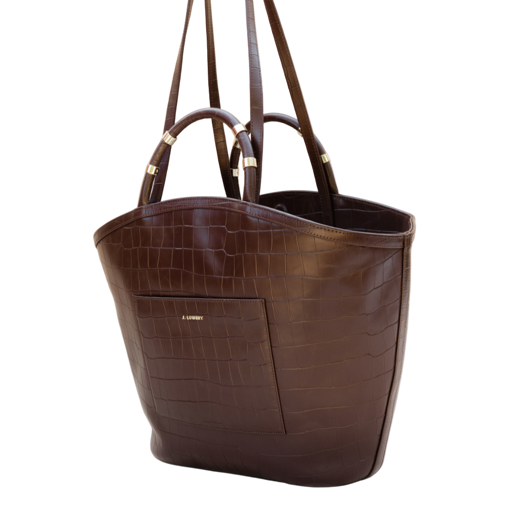 Brown leather tote bag with crocodile texture on a beige background