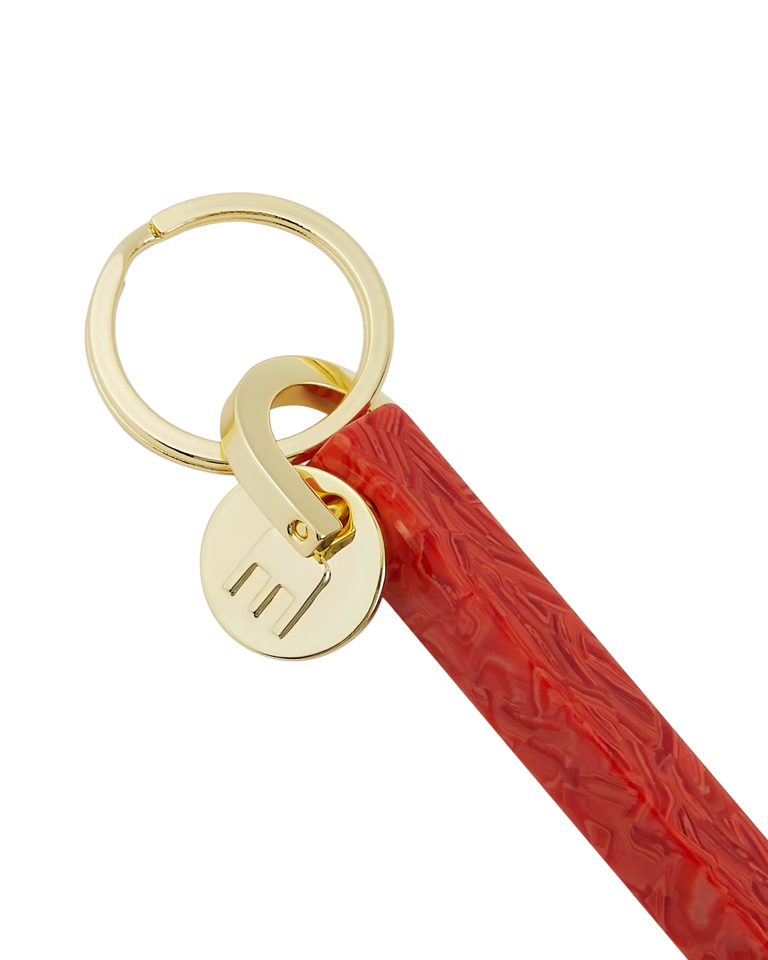 Red keychain with gold ring and circular tag on a white background