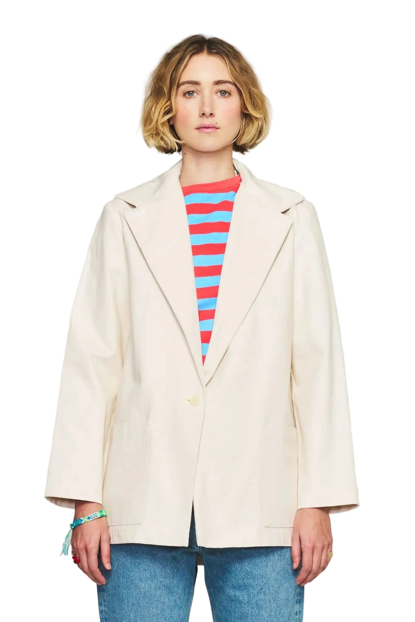 Person wearing a beige coat over a striped shirt with a plain background