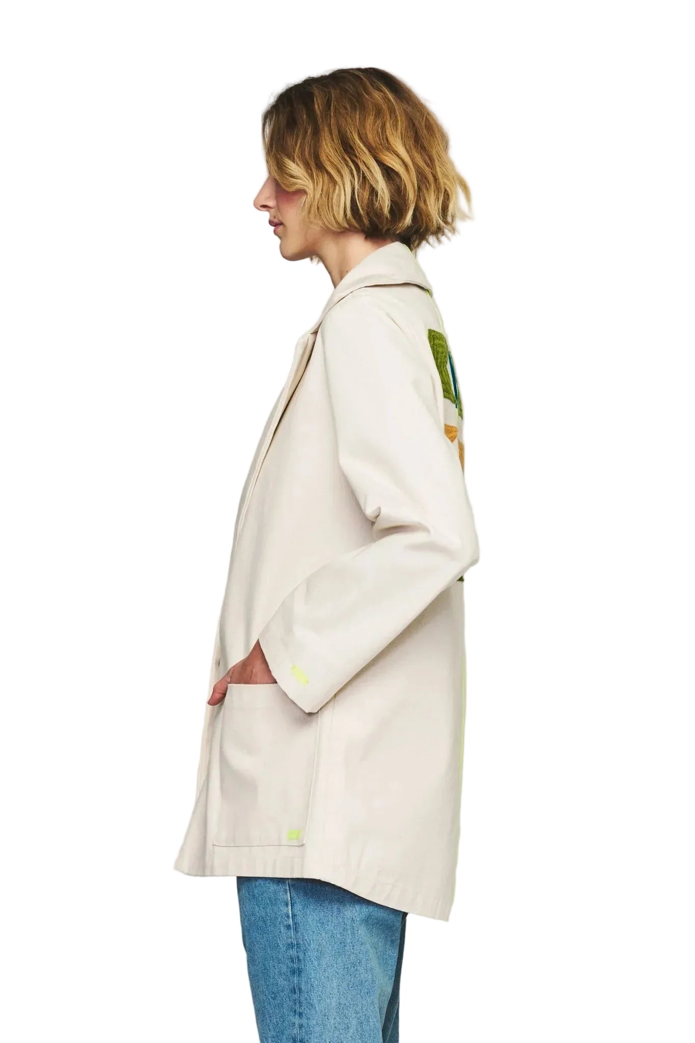 Person wearing a beige coat with floral patterns on a plain background