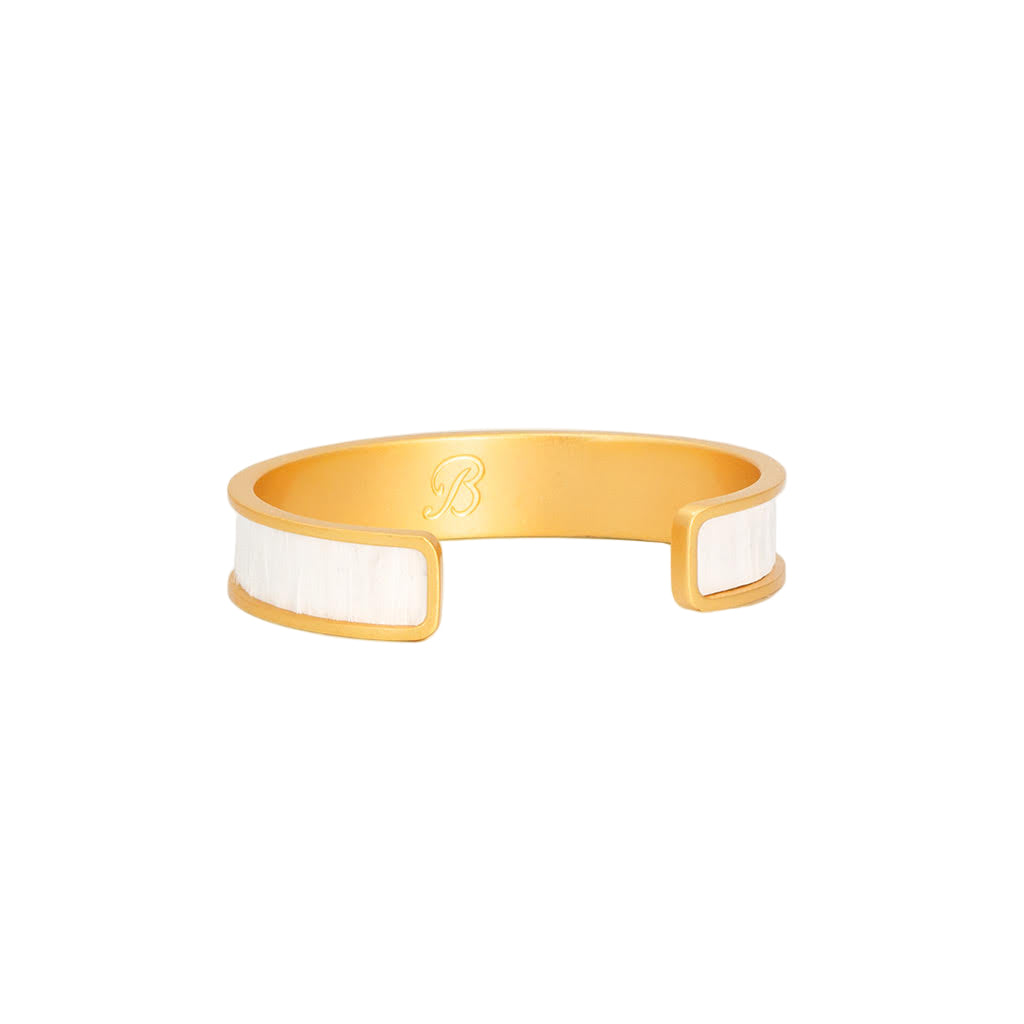 Gold and white bracelet on a light beige background