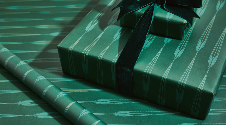 Gift wrapped in green Fieldshop wrapping paper on top of a sheet of wrapping paper
