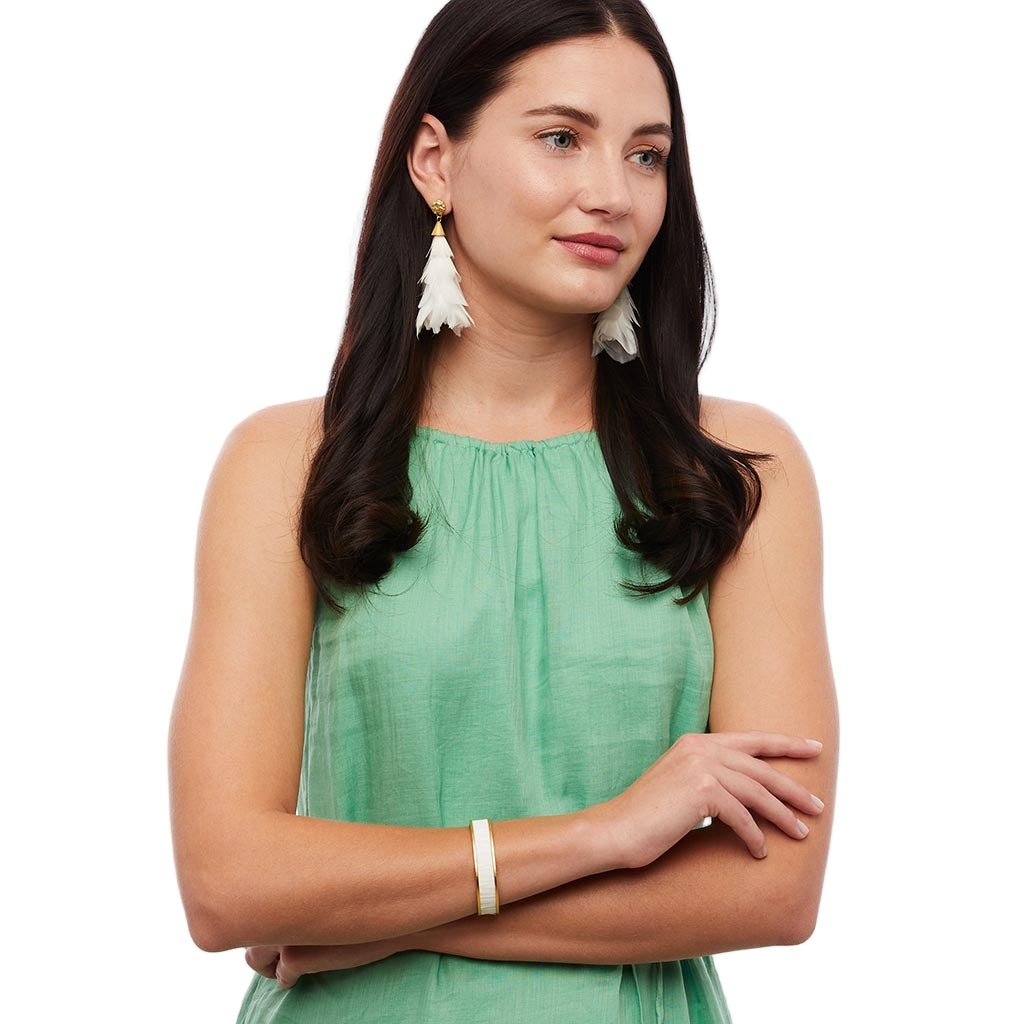 Woman wearing a green sleeveless top with white earrings on a white background