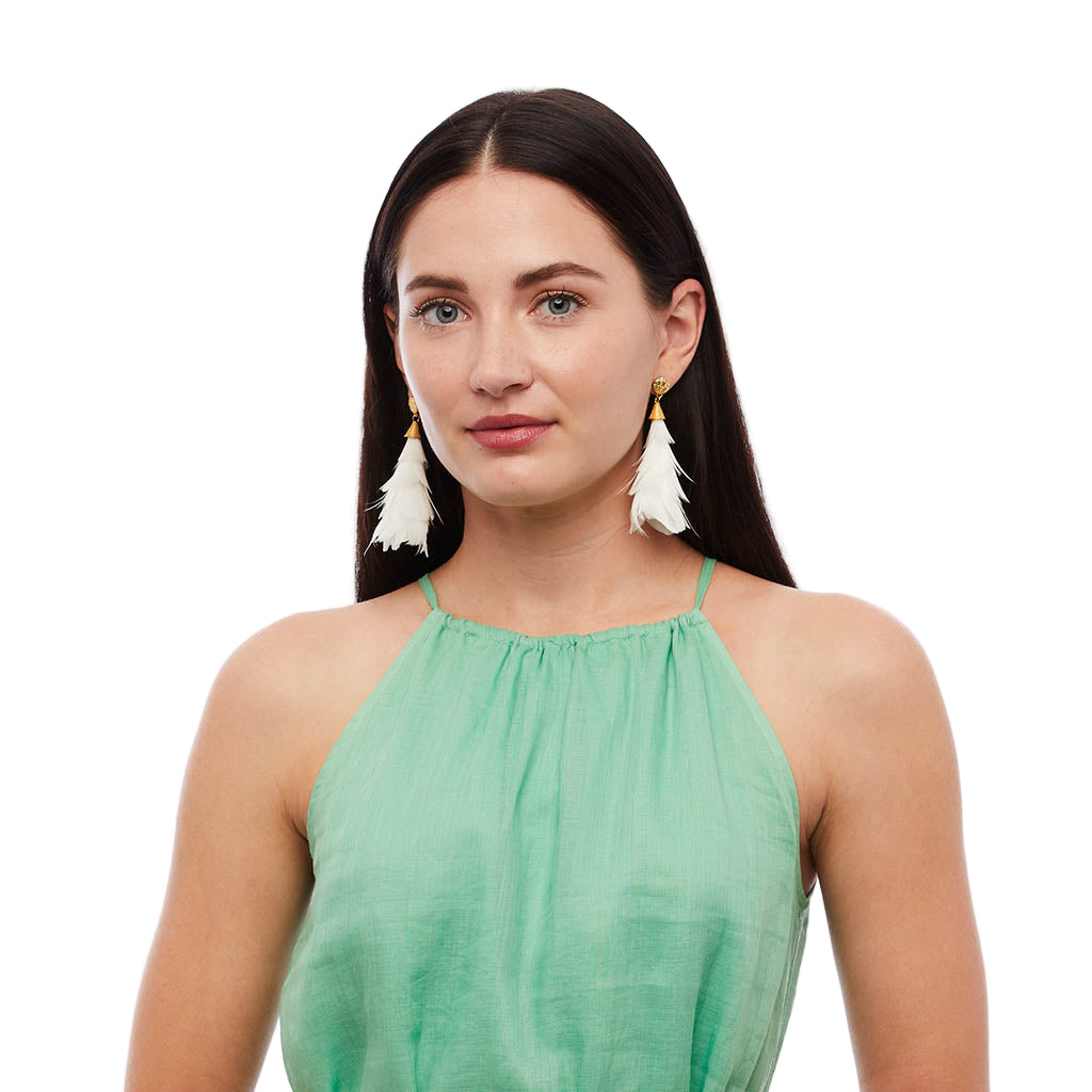 Woman wearing a green top and white feather earrings on a white background