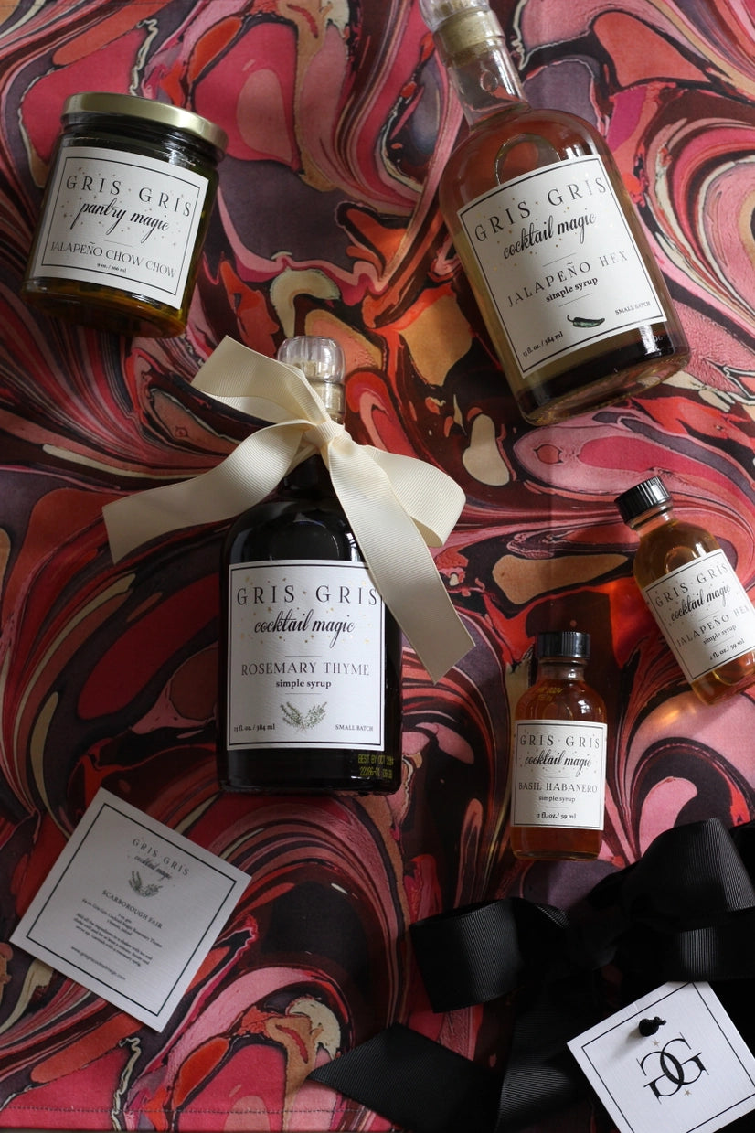 Collection of Gris Gris cocktail ingredients on a colorful marbled background